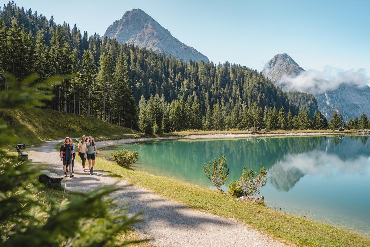 See mit Bergpanorama und Wanderern